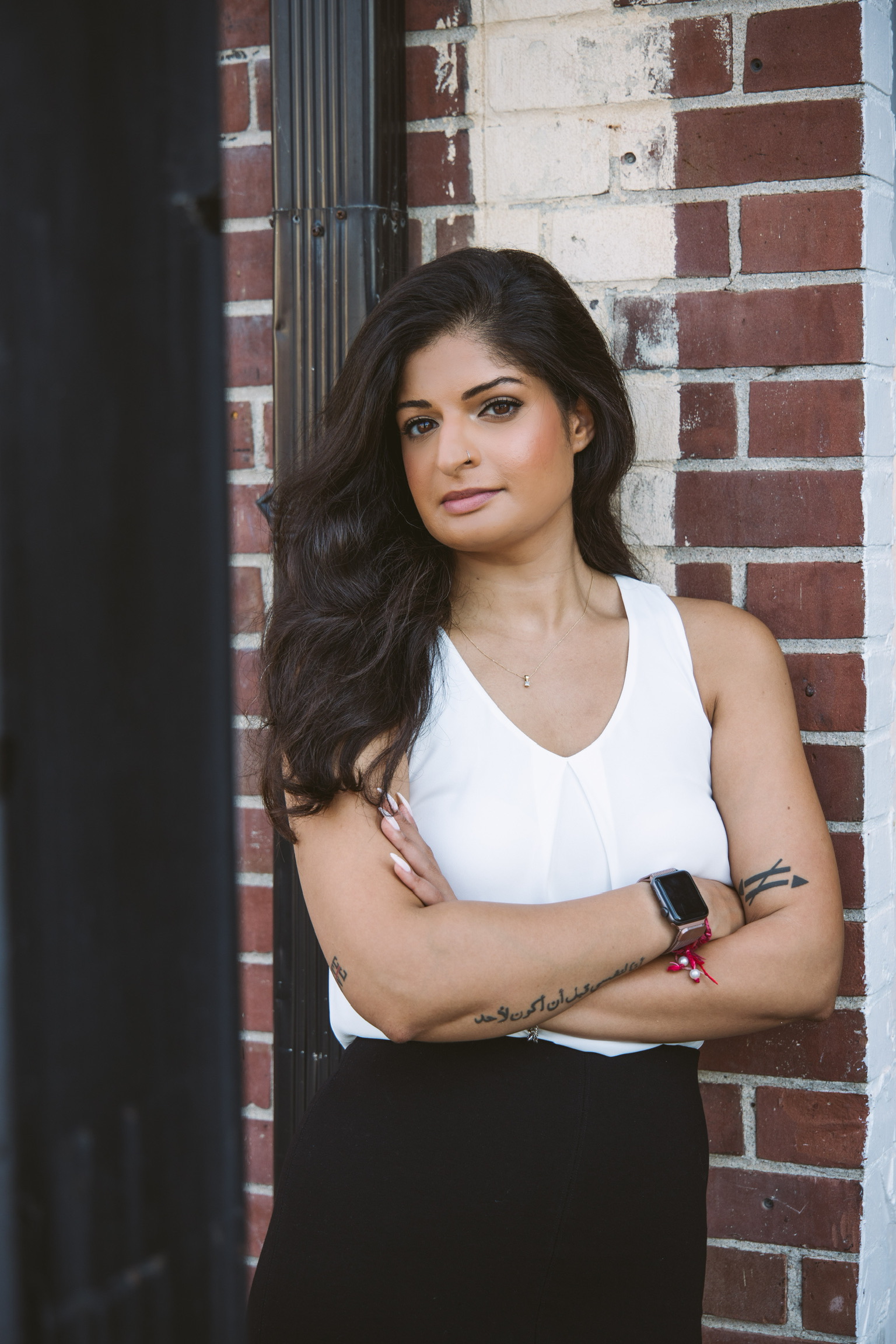 Portrait of Bhakti Chauhan, arms crossed against a brick wall.